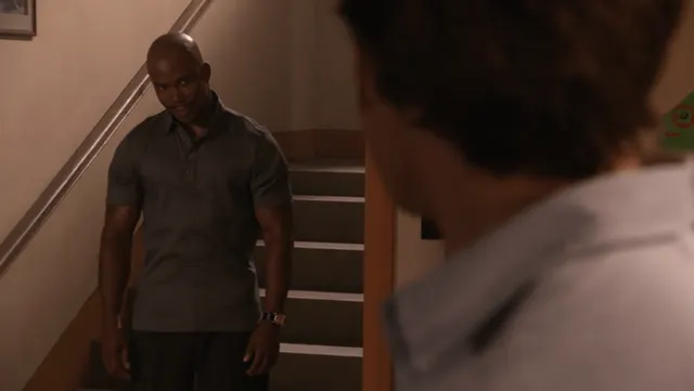 A man watching someone from the foot of a staircase